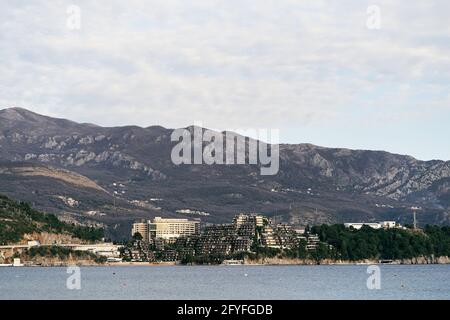 Blick vom Meer auf die Küste mit Häusern und Grüne Bäume vor der Kulisse der Berge Stockfoto