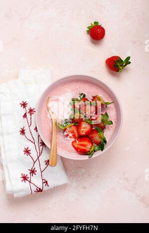 Frühstück mit Müsli, Kokosnuss und Erdbeer-Smoothie in einer Schüssel auf einem rosa hellen Hintergrund. Frühjahrs-Diät-Menü.Draufsicht Stockfoto