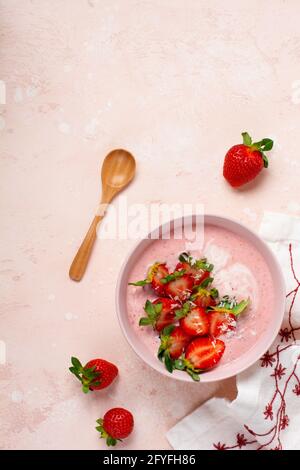 Frühstück mit Müsli, Kokosnuss und Erdbeer-Smoothie in einer Schüssel auf einem rosa hellen Hintergrund. Frühjahrs-Diät-Menü.Draufsicht Stockfoto