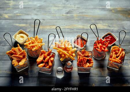 Von oben appetitlich gebratene Kartoffeln Chips Waffel und Crinkle Pommes frites mit Mayonnaise-Ketchup und Salz mit Pfeffer serviert Stockfoto