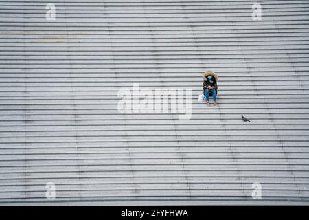 Person, die während einer Pandemie allein auf einer Treppe sitzt. Stockfoto