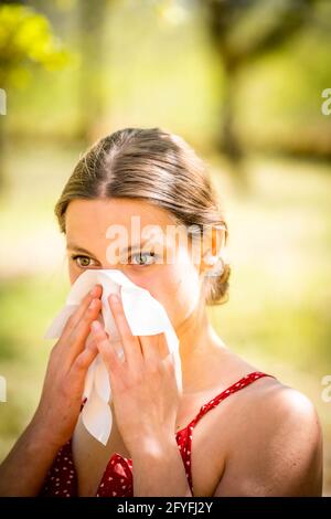 Frau mit Heuschnupfen, die ihre Nase weht. Stockfoto