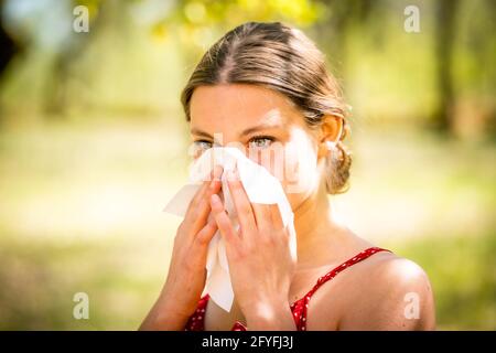 Frau mit Heuschnupfen, die ihre Nase weht. Stockfoto