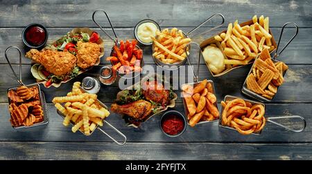 Blick von oben auf köstliche Junk-Food, einschließlich knusprigem Huhn und Pommes frites mit Ketchup-Mayonnaise und Salz mit Pfeffer Stockfoto