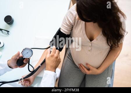 Nahaufnahme der männlichen Arzt Blutdruck messen der schwangeren Frau in Klinik Stockfoto