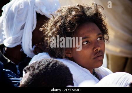 Äthiopisches Mädchen, das an der wahren Kreuzzeremonie inmitten einer Krone christlich-orthodoxer Gläubiger auf dem Berg Abuna Yoseph, Lalibela, Äthiopien, teilnimmt Stockfoto