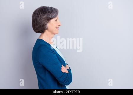 Profil Seitenportrait von schönen fröhlichen grauhaarigen Frau gefaltet Arme kopieren leeren Raum isoliert auf grauem pastellfarbenem Hintergrund Stockfoto