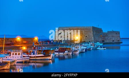 Heraklion auf der Insel Kreta, Griechenland. Hafen mit Fischerbooten an der alten venezianischen Festung in der Abenddämmerung Stockfoto