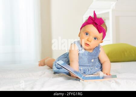 Kleine stilvolle Baby-Mädchen Blatt durch Buch im Bett Stockfoto