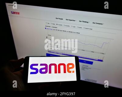 Person, die ein Smartphone mit dem Logo des britischen Vermögensverwaltungsunternehmens Sanne Group plc auf dem Bildschirm vor der Website hält. Konzentrieren Sie sich auf die Telefonanzeige. Stockfoto