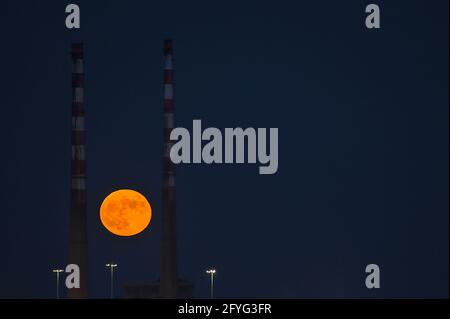 Wunderschöne Aussicht auf rote Superblumen der Mond steigt am irischen Himmel zwischen den berühmten Schornsteinen der Poolbeg Generating Station (Poolbeg CCGT) am 26. Mai 2021 auf f Stockfoto