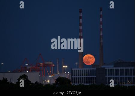 Wunderschöne Aussicht auf rote Superblumen der Mond steigt am irischen Himmel zwischen den berühmten Schornsteinen der Poolbeg Generating Station (Poolbeg CCGT) am 26. Mai 2021 auf f Stockfoto