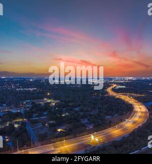 Wunderschöner Sonnenuntergang mit Langzeitbelichtung, aufgenommen in der Abenddämmerung in Tampa, Florida, mit erstaunlichen Wolken, Lichtspuren auf dem Highway und Pastellfarben. Stockfoto