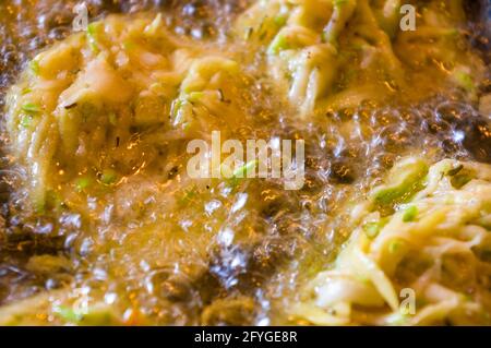 Gebratene Gemüsefritter mit Zucchini, Karotten, Kräutern, Eiern, Gewürzen und Käse in kochendem Öl, Nahaufnahme, selektiver Fokus Stockfoto