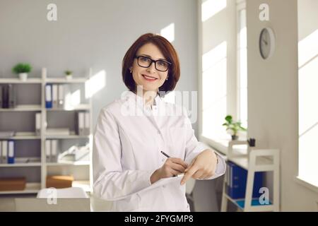 Porträt einer erfahrenen Ärztin mit Dokumenten in den Händen im Klinikbüro. Stockfoto