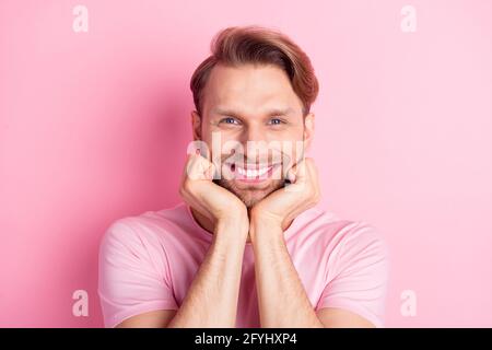Foto von attraktiven hübschen jungen Gentleman gekleidet Casual T-Shirt lächelnd Arme Kinn Wangen isoliert rosa Hintergrund Stockfoto