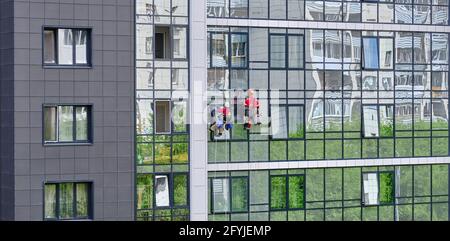 Jekaterinburg, Russland, 10. Mai 2020: Zwei Industriekletterer des Reinigungsdienstes waschen die Glasfassade eines modernen Hochhauses. Stockfoto