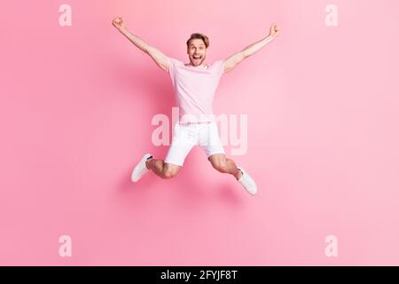 Ganzkörperportrait von entzückten Kerl offenen Mund heben die Arme Fäuste feiern gute Laune isoliert auf rosa Hintergrund Stockfoto