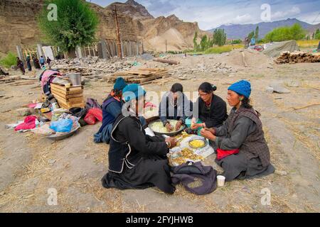 Mulbekh, Ladakh, Indien - 2nd. September 2014 : Ladakhi Stammesfrauen in traditionellen Kleidern schneiden Gemüse für die Zubereitung von Lebensmitteln für religiöse Feste Stockfoto