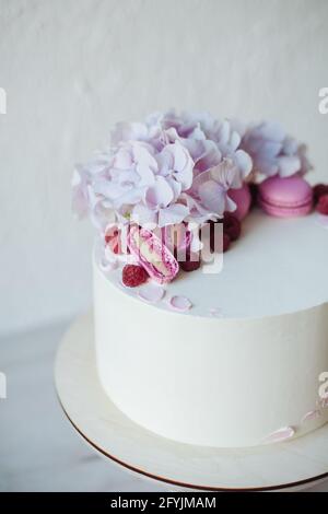 Nahaufnahme eines Buttercreme-Biskuitkuchens mit rosa Makronen und Hortensien-Blüten Stockfoto