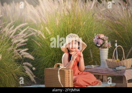 Lächelndes Mädchen, das einen Apfel hält, während es ein Picknick macht, Thailand Stockfoto