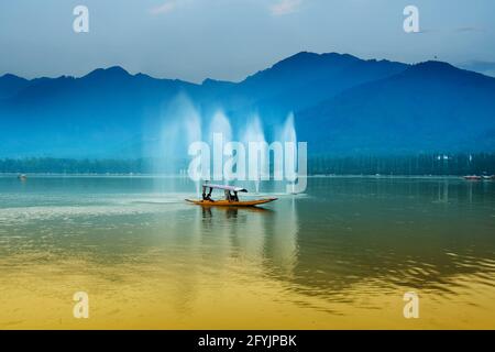 Spiegelung der Himalaya-Berge am Dal Lake, Srinagar, Jammu und Kaschmir, Indien. Hausboote schwimmen in der Nähe von Brunnen auf dem See am späten Nachmittag. Stockfoto