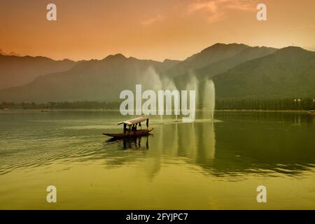 Spiegelung der Himalaya-Berge am Dal Lake, Srinagar, Jammu und Kaschmir, Indien. Hausboote schwimmen in der Nähe von Brunnen auf dem See am späten Nachmittag. Stockfoto