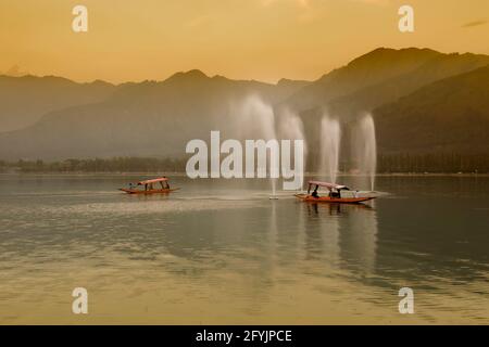 Spiegelung der Himalaya-Berge am Dal Lake, Srinagar, Jammu und Kaschmir, Indien. Hausboote schwimmen in der Nähe von Brunnen auf dem See am späten Nachmittag. Stockfoto