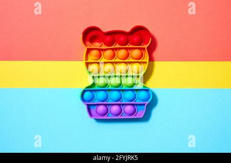 Trendige Pop-it-Spielzeuge in Form von Bären auf buntem gelben, roten und blauen Hintergrund. Draufsicht Flat Lay Stockfoto