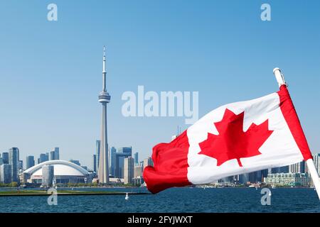 Die kanadische Nationalflagge und das Stadtbild von Toronto in Ontario, Kanada. Das gewölbte Dach des Rogers Center Baseballstadions und des CN Tower sind zu sehen Stockfoto