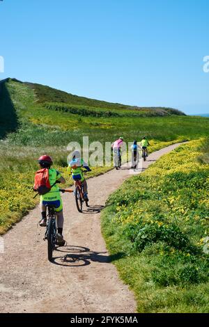 5. MAI 2018 - La Coruña, Galicien, Spanien: Gruppe von Radfahrern, die auf der Straße neben dem Herkules-Turm, umgeben von grünem Gras und Stockfoto