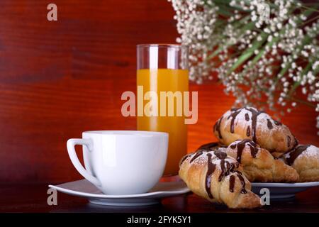 Kaffee, Croissant und Orangensaft auf brauner Oberfläche Stockfoto