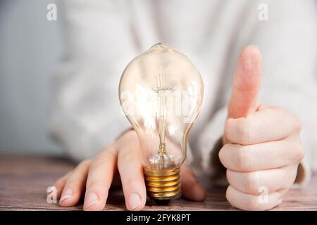 Leuchtende Glühbirne mit Daumen nach oben, gute Idee und Brainstorming, kreative Wirtschaft oder Bildung Konzept Hintergrund modernen Stil Stockfoto