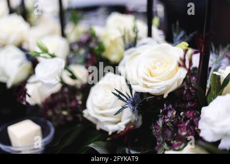 Wunderschöne weiße Rosen mit grünen und violetten Akzenten in einem Formelles Abendessen im Mittelpunkt Stockfoto