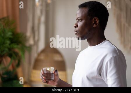 Afrikanischer Athlet zu Hause mit einem Glas Wasser nach dem Sporttraining. Stockfoto