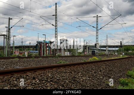 KÖLN, DEUTSCHLAND - 23. Mai 2021: Eisenbahnstrecke und Stromleitungen für Züge mit launisch bewölktem Himmel in Köln Stockfoto