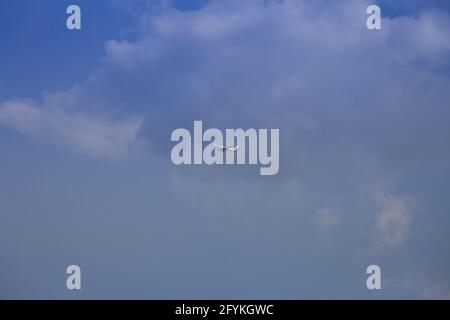 Propellerflugzeug von der Sonne gegen einen blauen Himmel beleuchtet Mit weißen Wolken und Baum - in Bewegung Stockfoto