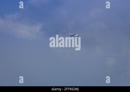 Propellerflugzeug von der Sonne gegen einen blauen Himmel beleuchtet Mit weißen Wolken und Baum - in Bewegung Stockfoto