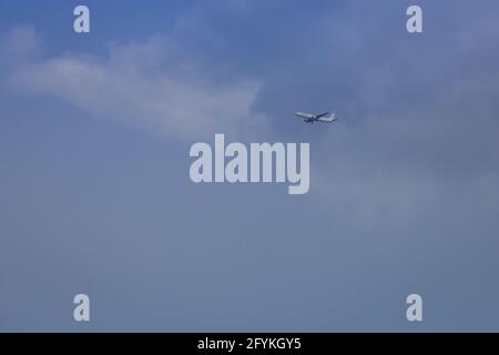 Propellerflugzeug von der Sonne gegen einen blauen Himmel beleuchtet Mit weißen Wolken und Baum - in Bewegung Stockfoto