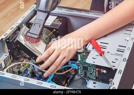 Entfernen Sie mit dem Staubsauger Staub von der Festplatte des Desktop-PCs. Stockfoto