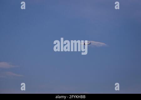 Propellerflugzeug von der Sonne gegen einen blauen Himmel beleuchtet Mit weißen Wolken und Baum - in Bewegung Stockfoto