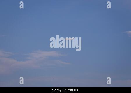 Propellerflugzeug von der Sonne gegen einen blauen Himmel beleuchtet Mit weißen Wolken und Baum - in Bewegung Stockfoto