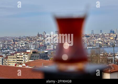 Armudu mit türkischem schwarzem Tee sitzt auf einer Dachzaunsäule vor dem Stadtbild Istanbuls, Schwerpunkt auf dem Hintergrund. Stockfoto