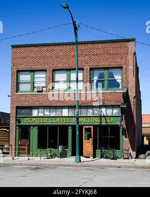 CLE Elum, WA, USA - Mai 26. 2021; Pioneer Coffee Roasting Company Ziegelgebäude mit gelbem Schild gegen grüne Fassade in der Innenstadt von Cle Elum Stockfoto