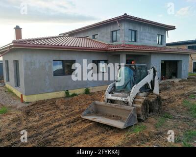 Kleine Bodenarbeiten Bulldozer auf der Baustelle vor Individuelles Haus im Bau Stockfoto