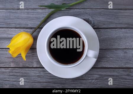 Tasse Kaffee und Tulpenblume auf Holzhintergrund, High-Angle-Shot Stockfoto
