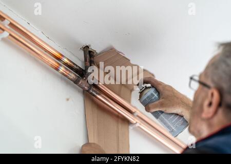 Unbekannter Mann, der während der Bemalung von Heizungsleitungen an der Wand war Installationsprozess Stockfoto