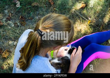 Unschärfe blonde kleine Mädchen spielt mit Katze, schwarz und weiß kleine Kätzchen. Natur grün Sommer Hintergrund. Mädchen streichelte Haustier. Love Animals Konzept. Bis Stockfoto