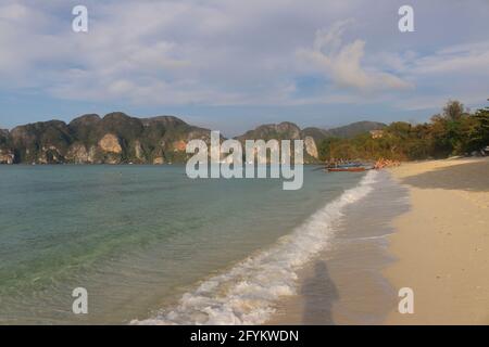 Schöner Sandstrand mit festgetäuten Longtail-Booten im Hintergrund. Stockfoto