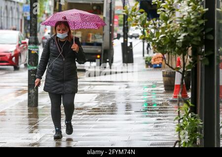 London, Großbritannien. Mai 2021. Eine Frau mit Gesichtsmaske schützt vor Regen unter einem Regenschirm in London. (Foto: Dinendra Haria/SOPA Images/Sipa USA) Quelle: SIPA USA/Alamy Live News Stockfoto